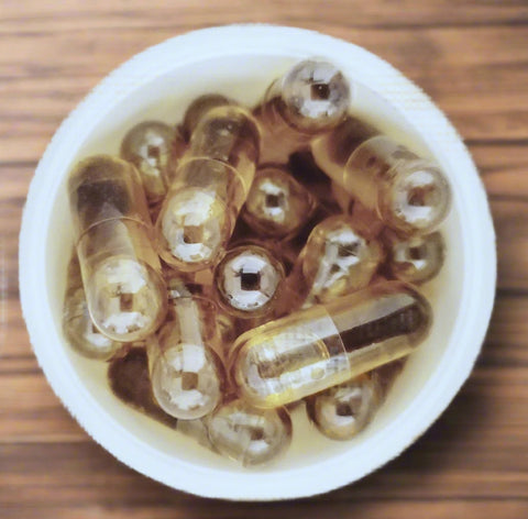 This image displays a collection of CBD oil capsules, each encapsulated in a clear shell and filled with a yellowish substance, likely the CBD extract. The capsules are arranged neatly in a white container, highlighting their uniform shape and size.